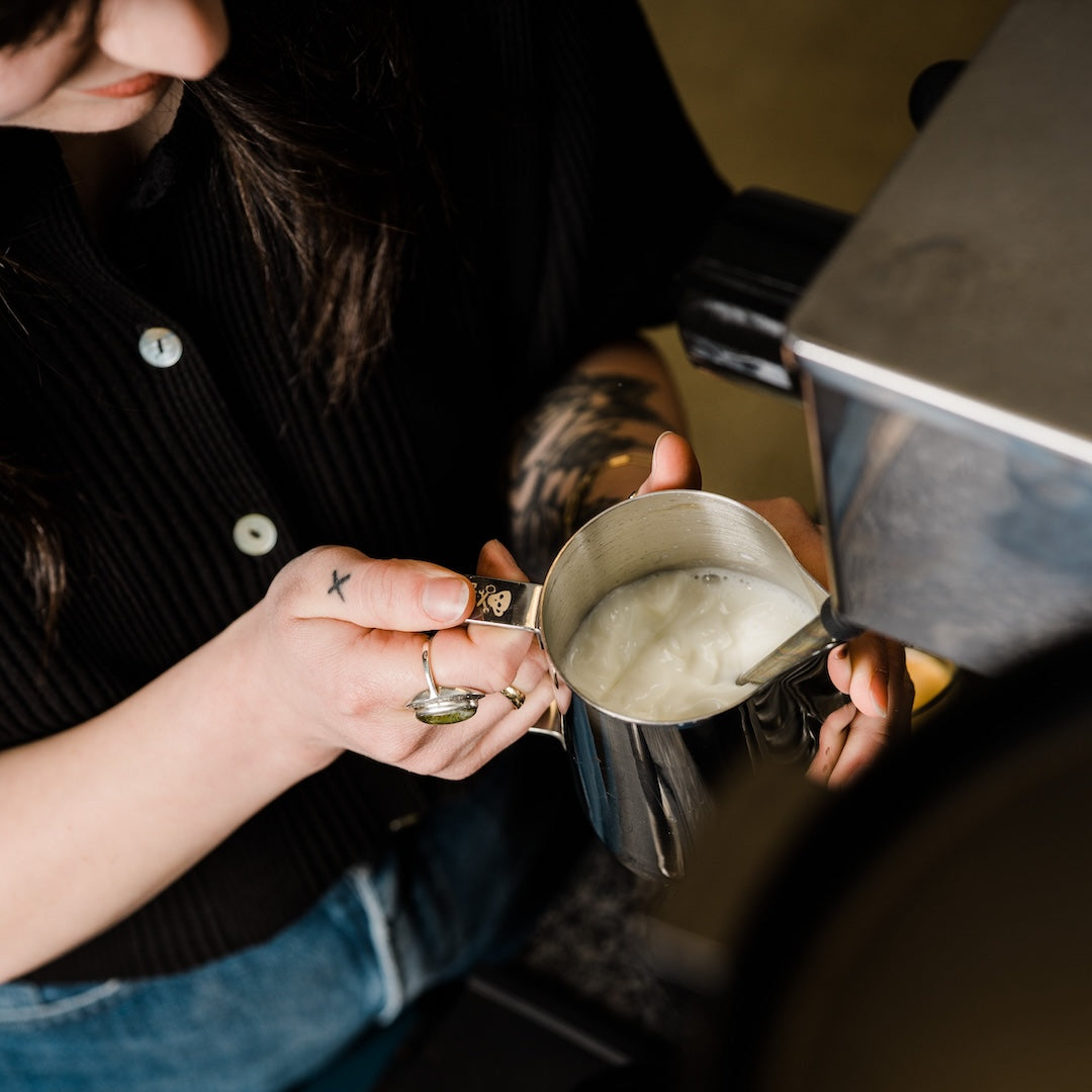Person steaming milk on an espresso machine.