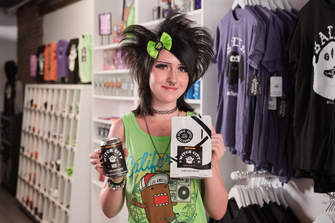 Georgia Wrenn in Georgia's Little Salem Shop, holding the 2026 Witch City bag and cold brew can.