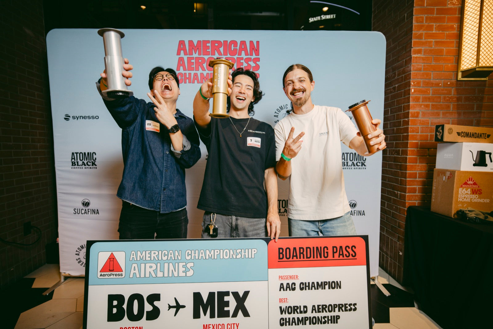 The 2026 podium celebrating with AeroPresses and the Boston to Mexico City boarding pass